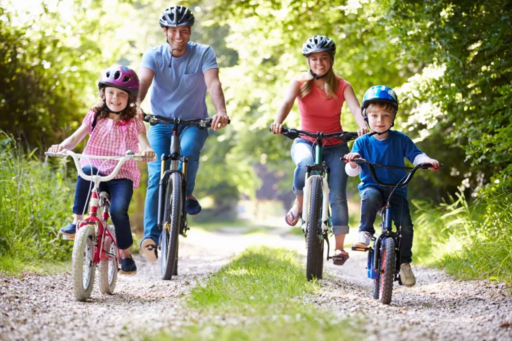 Family riding bicycles together on a wooded trail